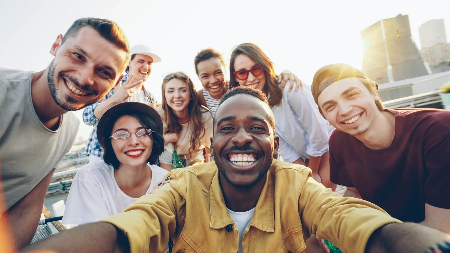 A diverse group of young friends laughing together on a rooftop at golden hour