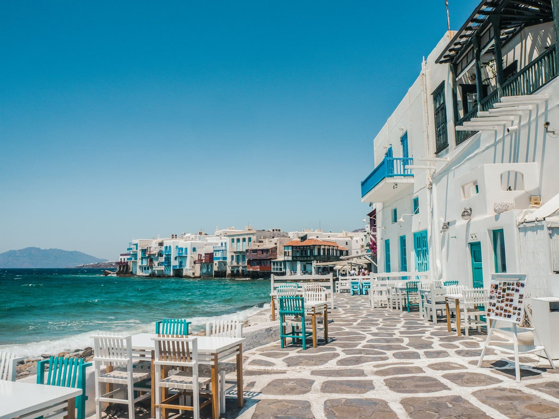 Whitewashed houses above turquoise water in Mykonos