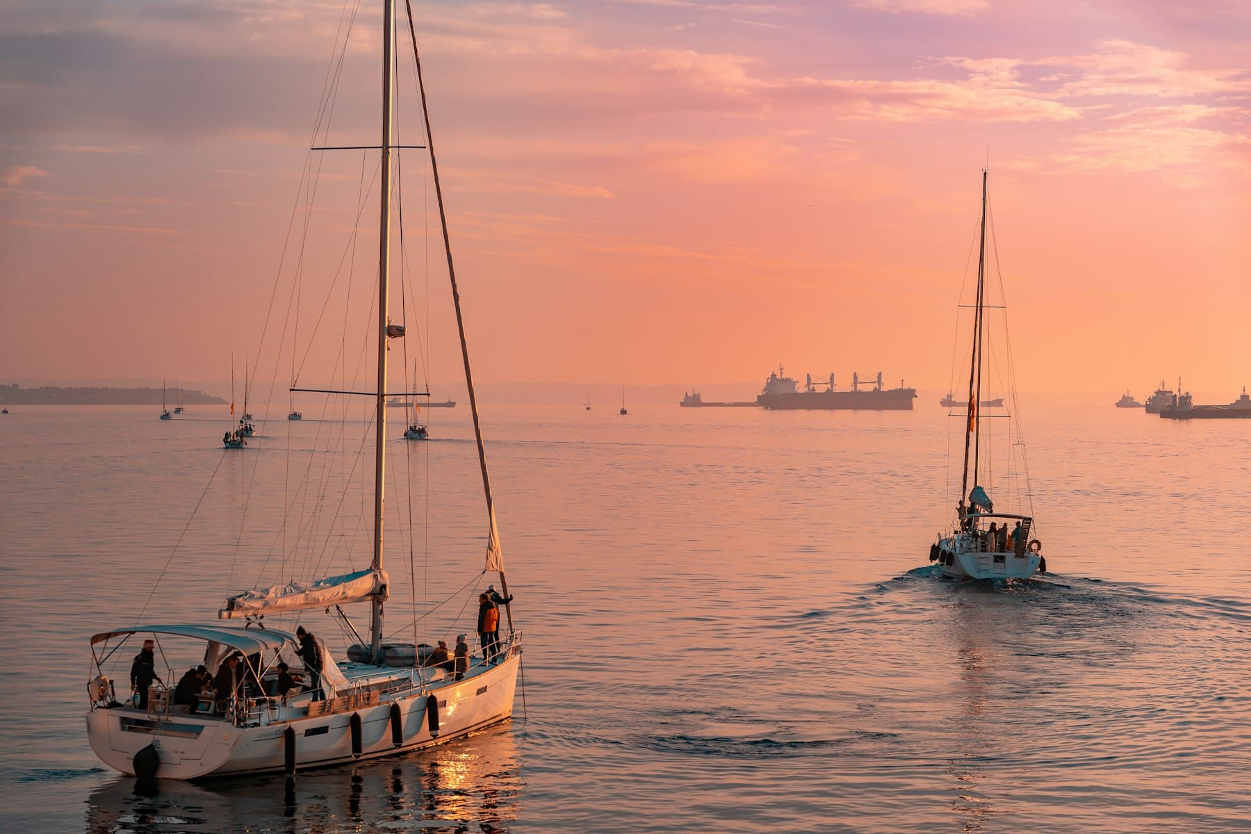 Sailing boats coming into harbour at sunset over a calm sea