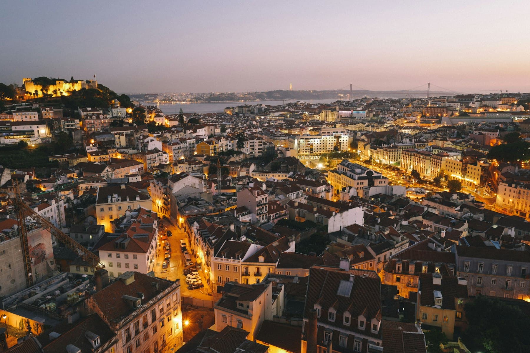 Lisbon at dusk from above, the castle lit and the Tagus beyond