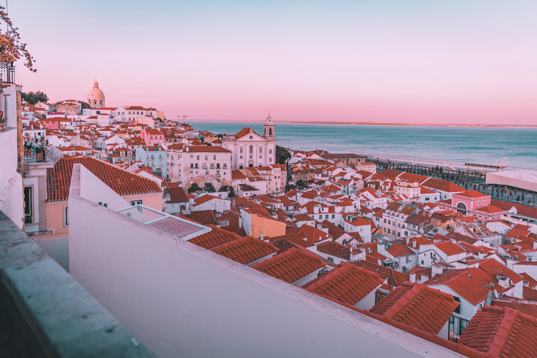 Alfama rooftops at pink dusk above the Tagus
