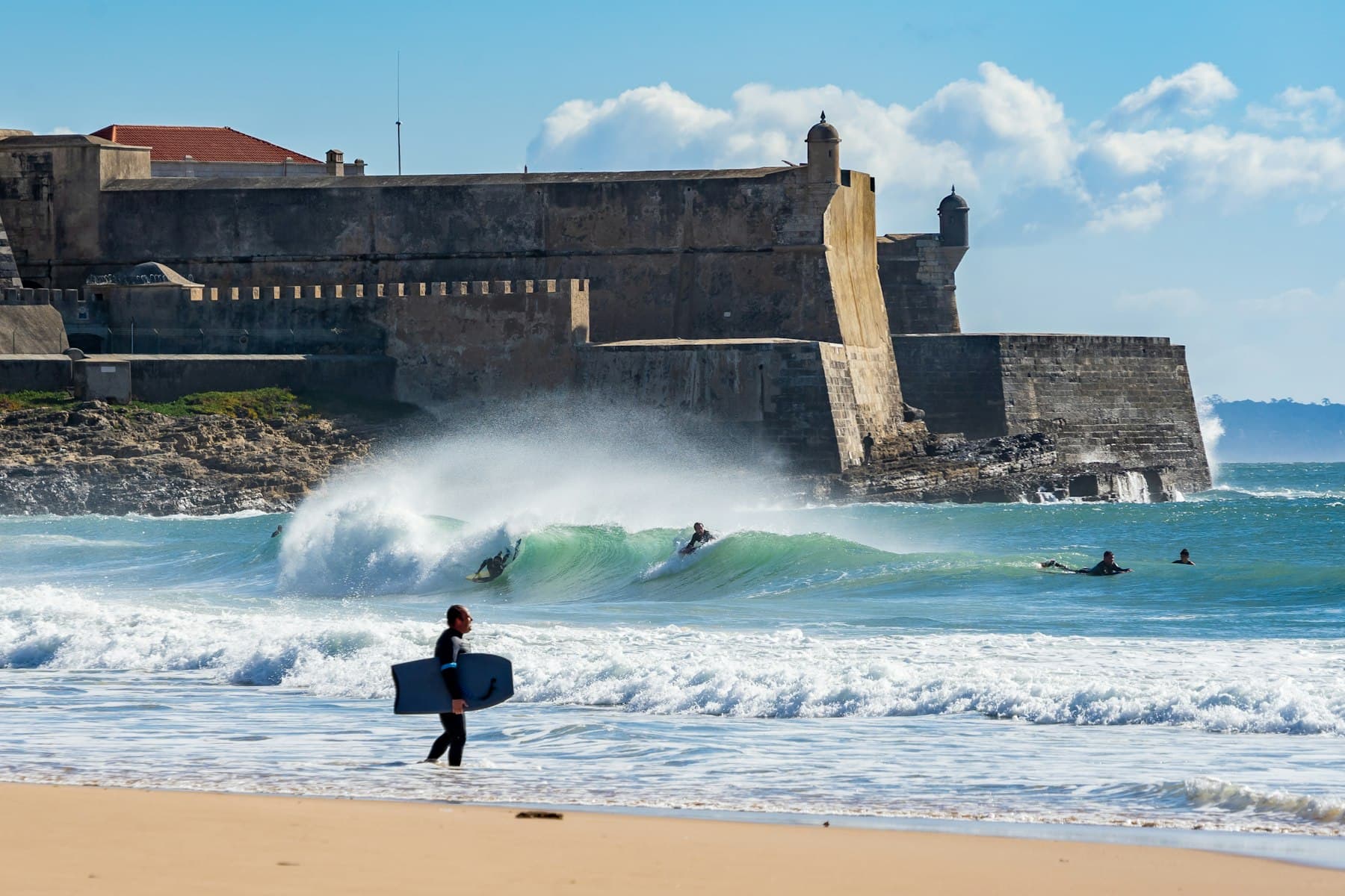 A surfer walking out at a Portuguese beach break